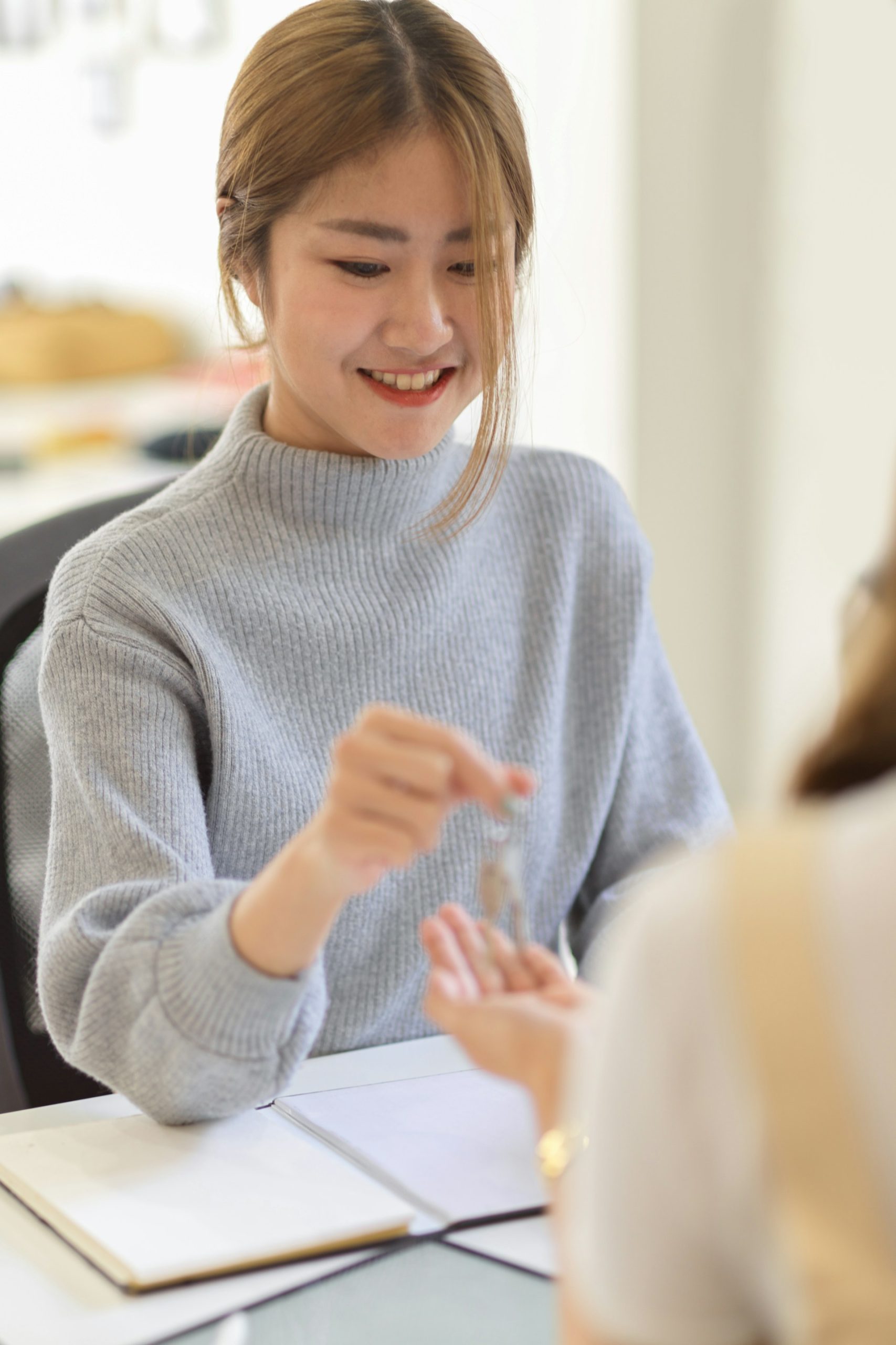 beautiful-asian-real-estate-agent-giving-a-house-key-to-new-buyer-after-signing-a-house-contract-in-the-office